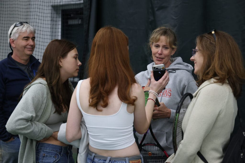 Family and friends of Lucy Guerra show photos and share stories with her mother Amy Guerra by showing photos on their phone.