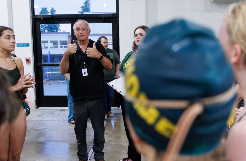 Don Helling gives his team two thumbs up after hearing the Mariners beat Squalicum as swimmers surround him.