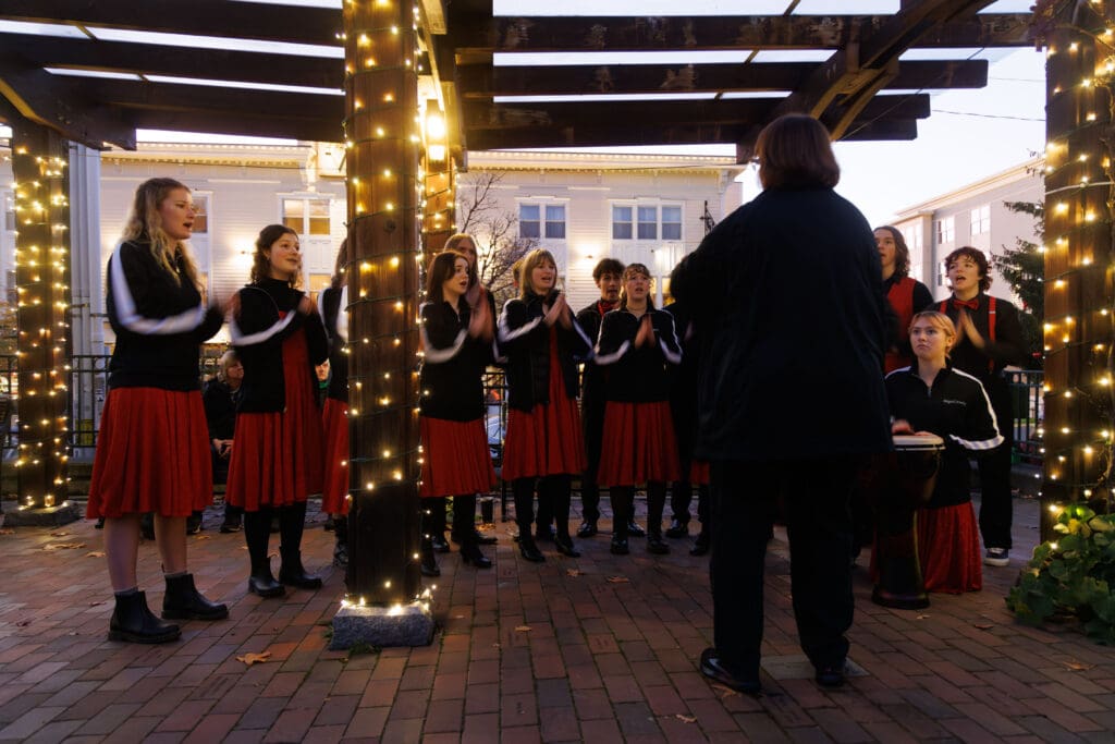 The Bellingham High Showstoppers choir performs with their hands put together and wearing their signature red and black attire.