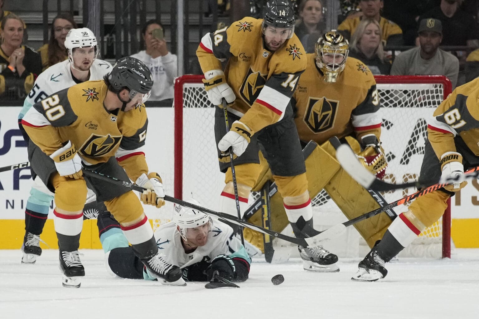 Seattle Kraken center Jaden Schwartz dives to try and knock the puck away from the goal as he is surrounded by Vegas Golden Knights players.