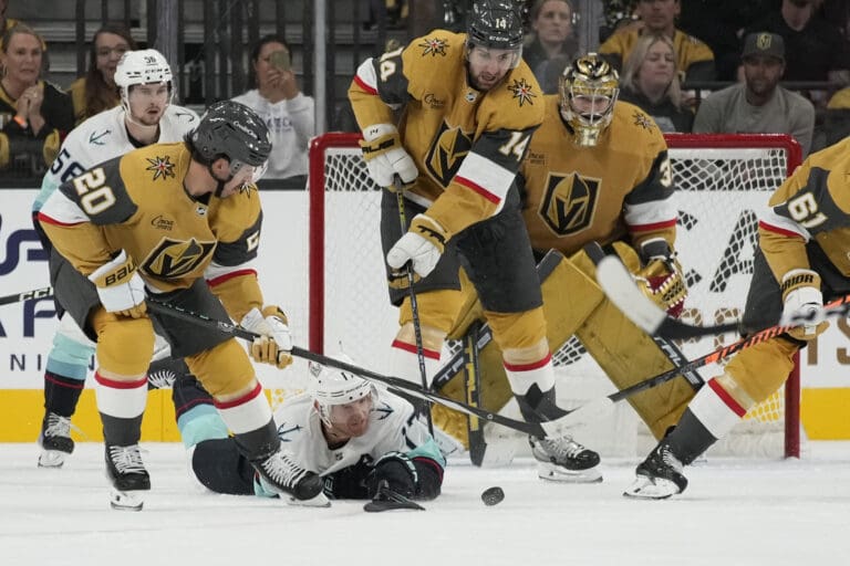 Seattle Kraken center Jaden Schwartz dives to try and knock the puck away from the goal as he is surrounded by Vegas Golden Knights players.