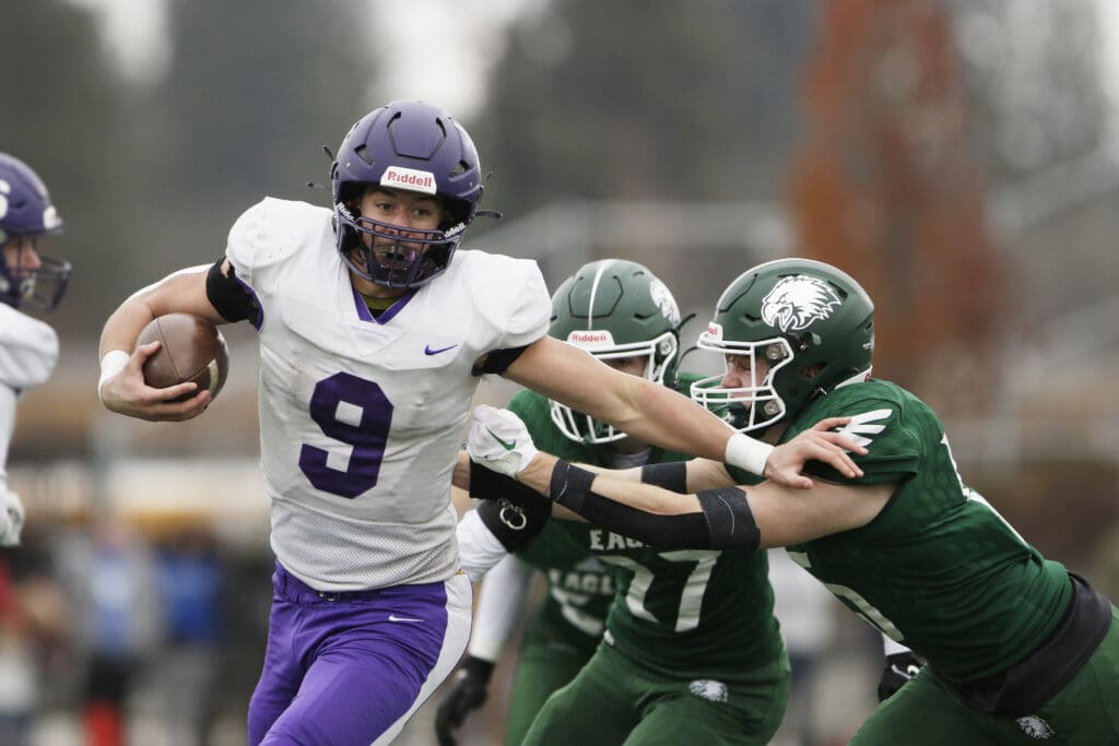 Nooksack Valley’s Colton Lentz (9) carries the ball while other players reach to grab him from the sides.