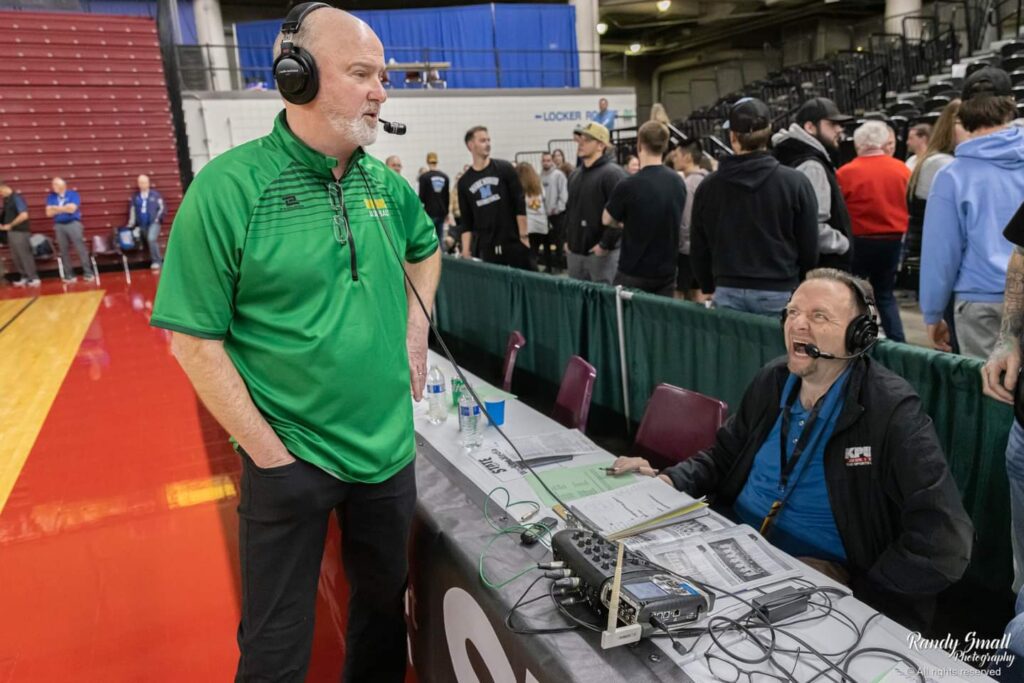 Mark Scholten, right, interviews Lynden boys basketball coach Brian Roper by the table as people behind them start to leave.