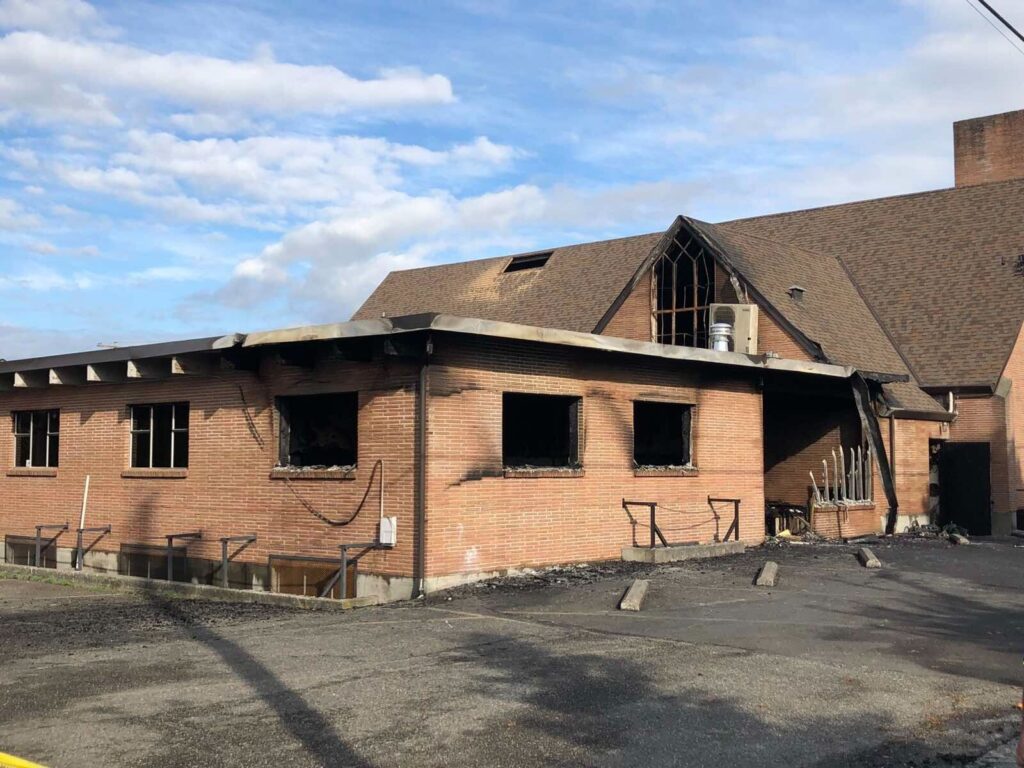 The outside of the church that survived the fire where the window glass is missing and the bricks outside have traces of black soot from the fire.