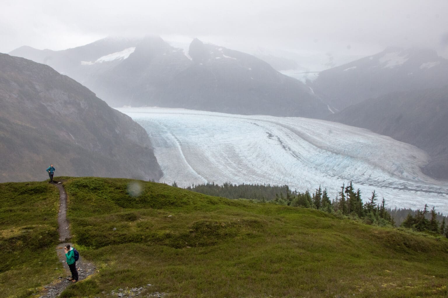 An aerial view of the grassy field overlooking the icey mountains and waters.