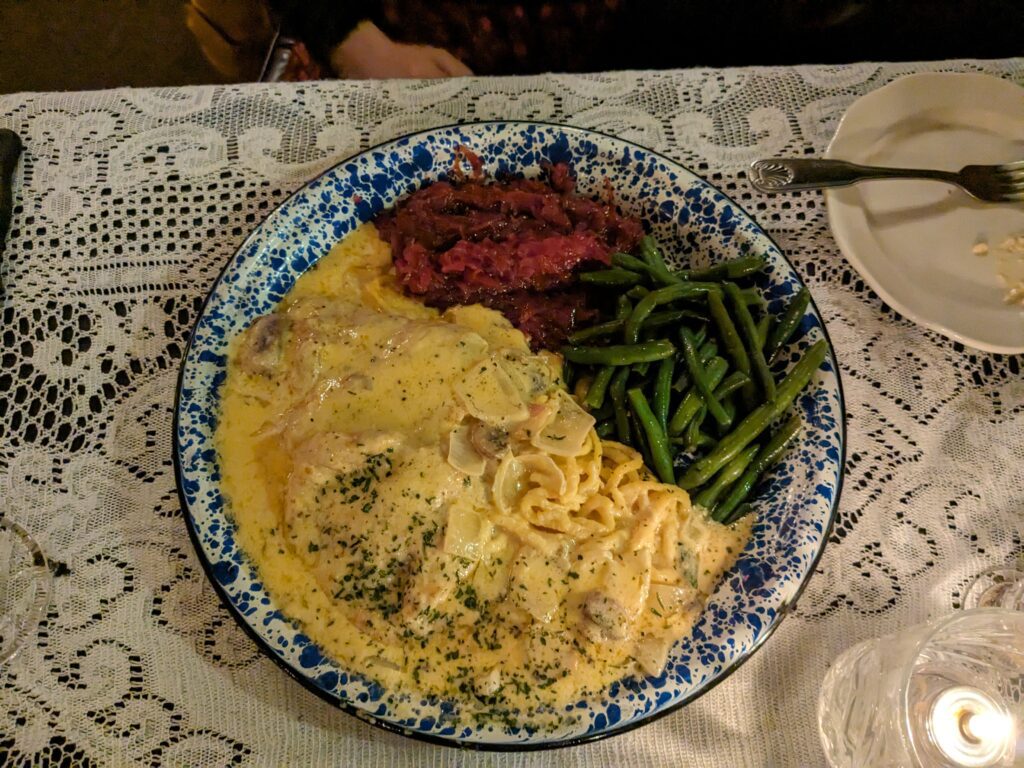 The Jaeger schnitzel is fresh spaetzle, pork cutlets, and hearty creamy mushroom sauce served on a blue and white bowl.