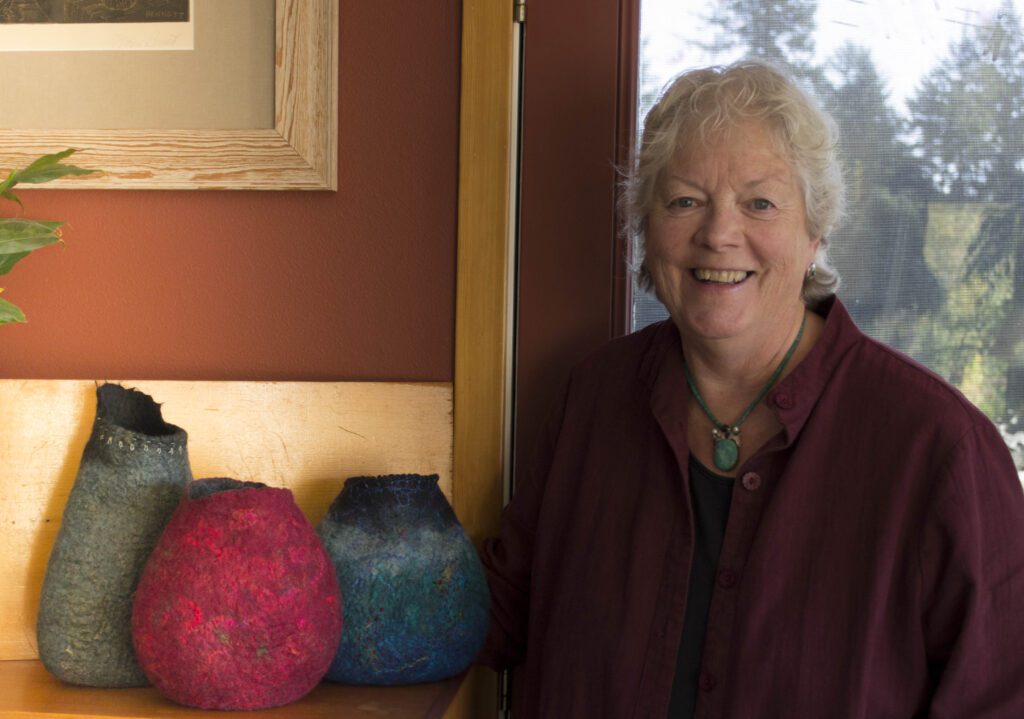 Sue McCaslin smiles for the camera next to her hand-felted vessels.