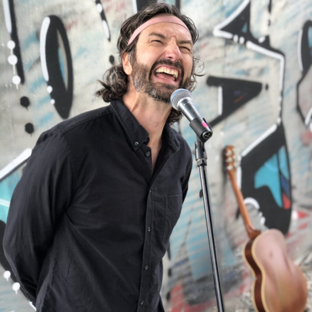 David Milchard presents "Citizen Hurricane: The World’s Greatest Improvised Rock & Roll Comedy Act … in the World!" with an acoustic guitar propped up behind him.