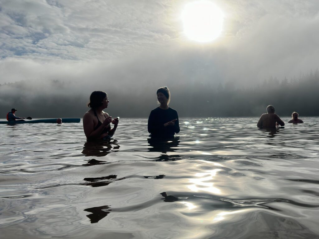 Padden Polar Dip participants enjoying the waters as some remain submerged while a kayaker idles nearby.