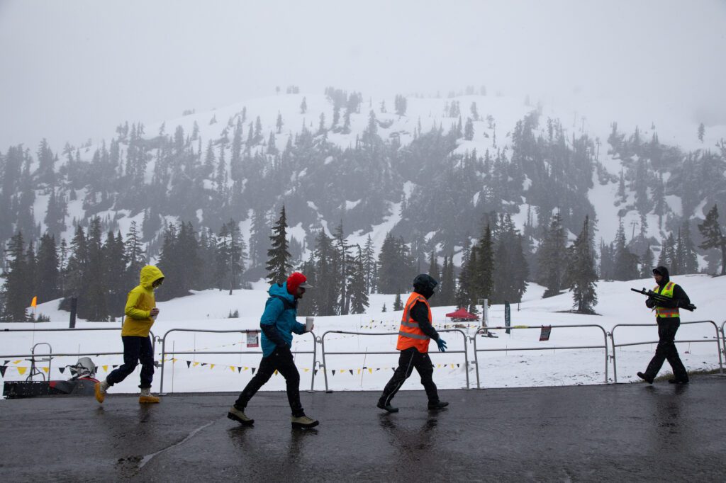 Volunteers walk around the course as snow falls, shrouding Pan Dome at Mt. Baker Ski Area.