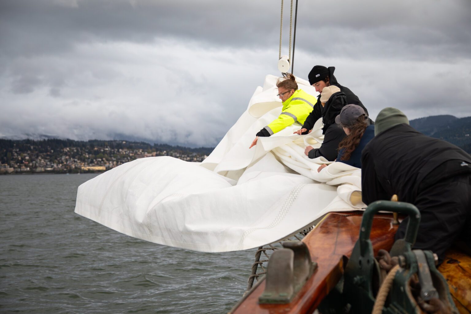 Former first mate Brandy Curran, in yellow, leads the crew in storing the jib sail as the schooner Zodiac returns to Bellingham on April 28 after a training cruise.