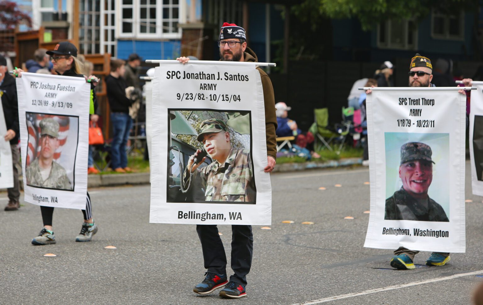 Members of the William Matthews Veterans of Foreign Wars Post/Auxiliary 1585 walk with photos of fallen soldiers from Whatcom County.