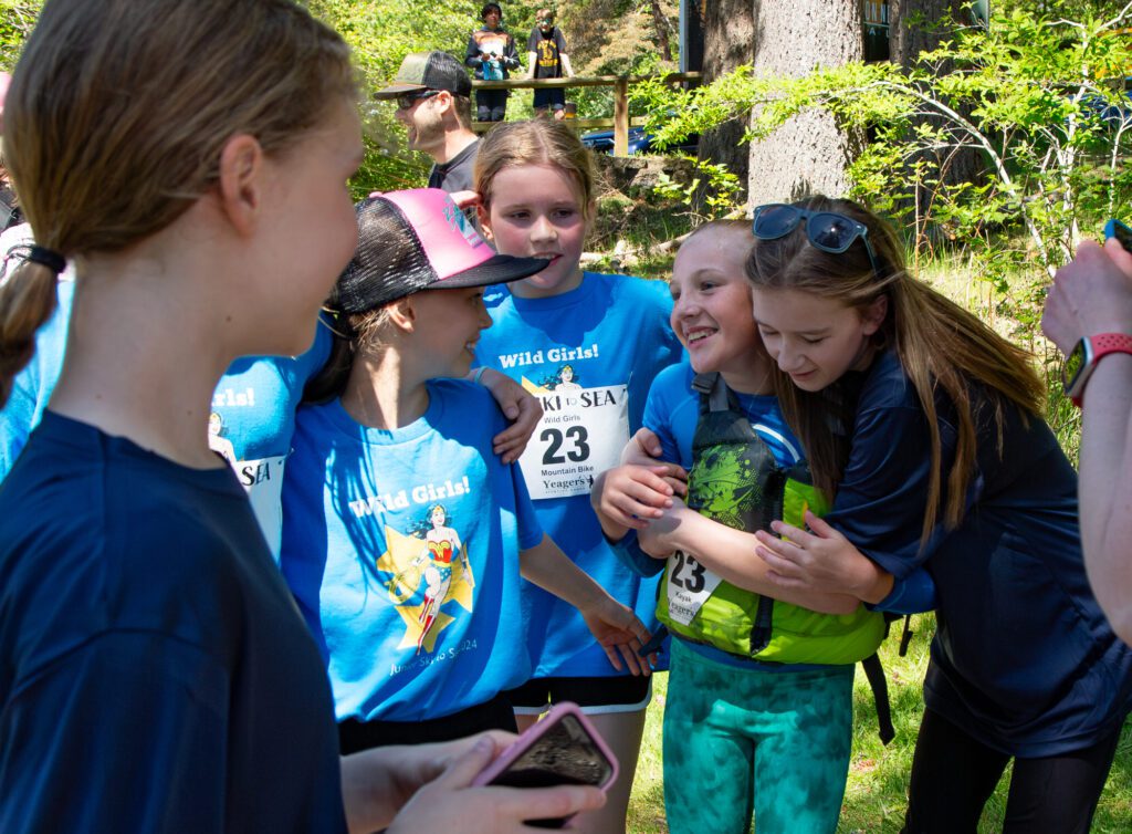 Kayaker Sawyer Smith gets a hug while celebrating finishing the race with her team Wild Girls. They placed second in the elementary school girls division with a time of 50:59.