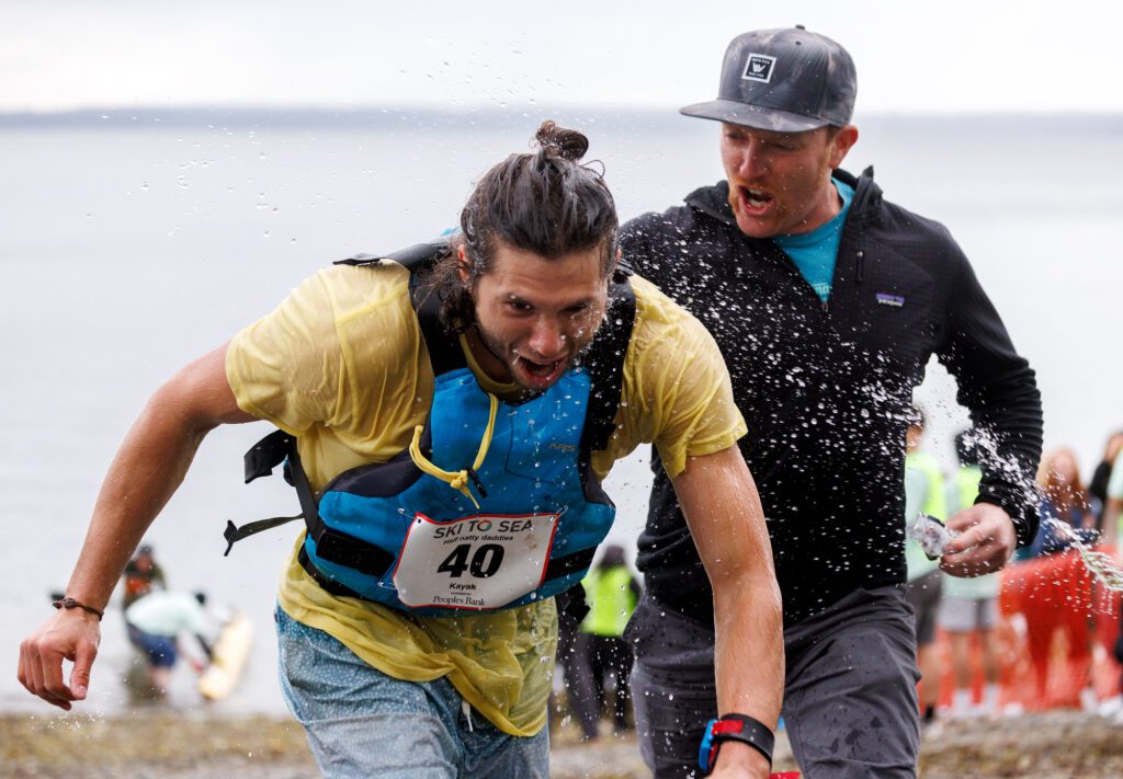 Kayaker Koal Reyes-Schulze gets sprayed with water as Zach Gillis encourages him to sprint to the finish line of the 2024 Ski To Sea Race on May 26 in Bellingham.