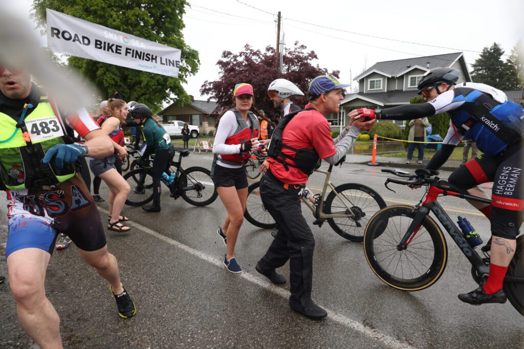 It’s a mad scramble as canoers grab timing chips from their road bike partners and race to their boats from the exchange area.