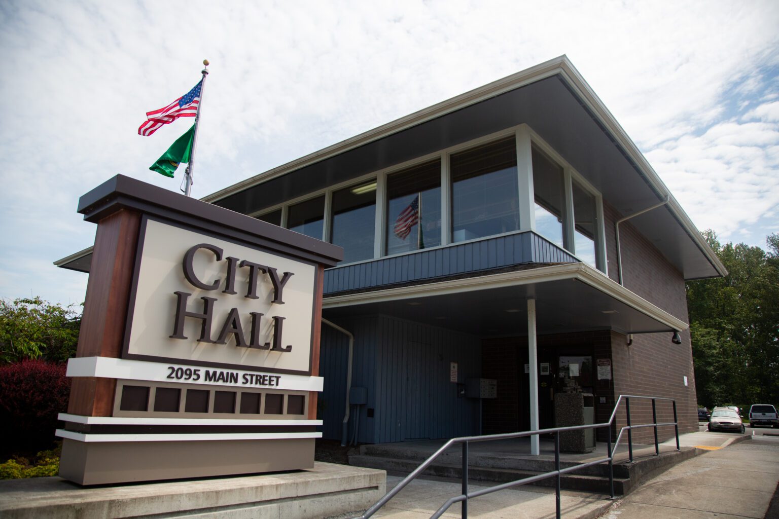 The front of Ferndale City Hall has flags flying over the outdoor sign.