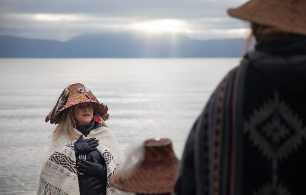 Raynell Morris, a member of the Lummi Nation and vice president of the Sacred Lands Conservancy, talks to attendees while wearing traditional garb over her winter clothes.