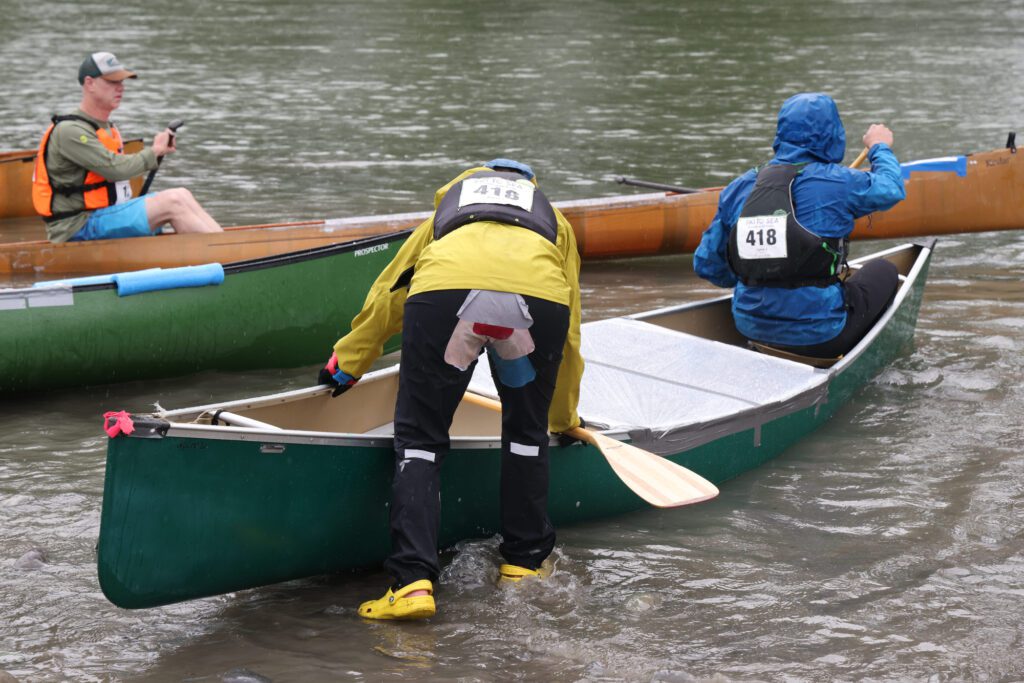 A canoe racer’s pants show wear and repairs from sitting during the canoe leg.