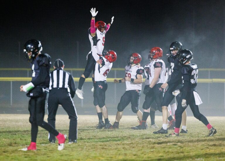 Mount Baker's Marcques George is hoisted into the air by teammate Alex Maloley near his teammates and other players while a referee watches.