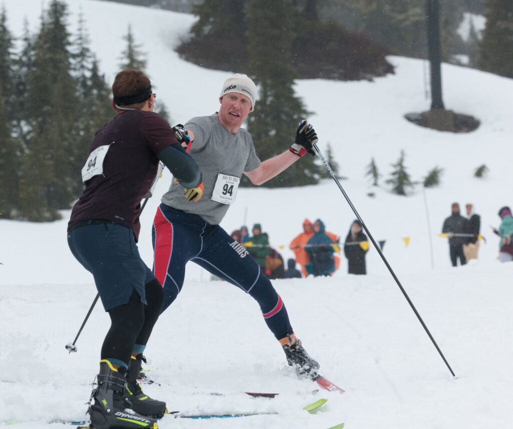 Cross-country skier Mike Hinckley passes off the timing chip to teammate Nathan Spencer. Hinckley, of team Inn at Lynden, was the first to finish the cross-country leg with a time of 21:37.8.