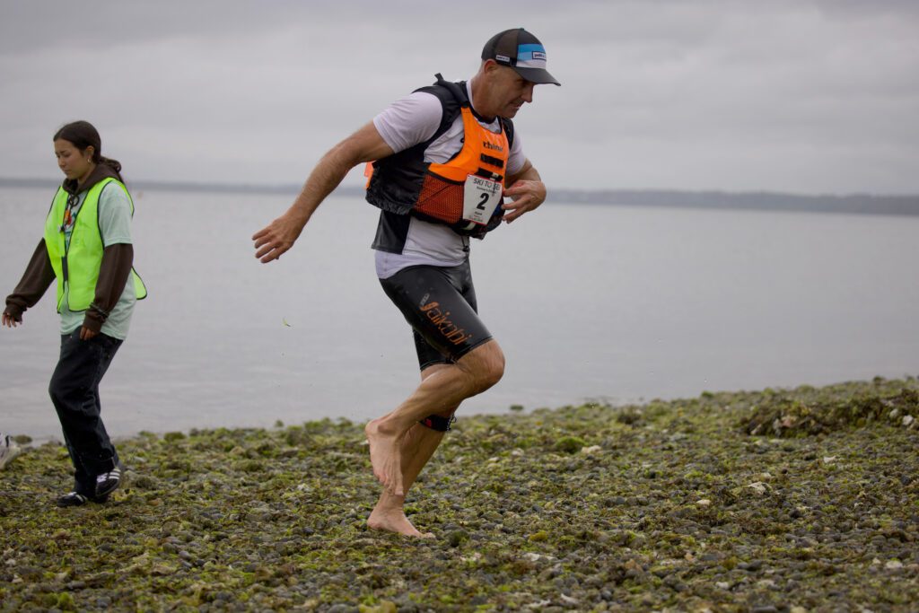 Greg Redman of team Boomer's Drive-In runs on the rocky beach as he finishes the leg second.