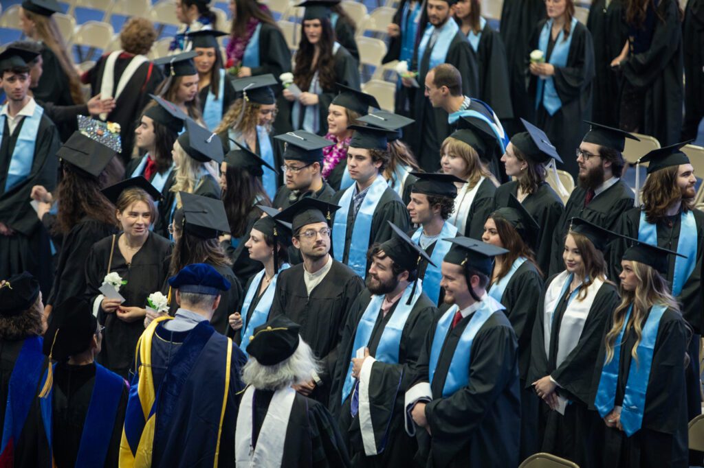 Graduates look around Carver Gym for family, friends and supporters as they arrive to their commencement ceremony.