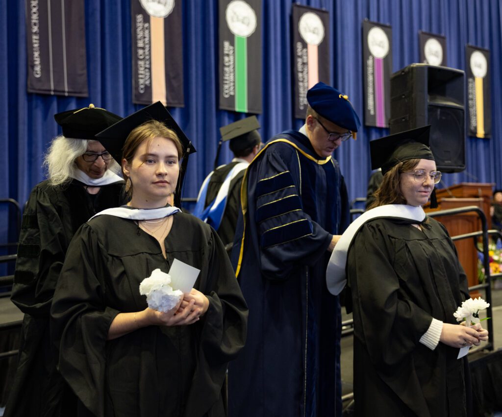 Isabella Arnett, left, and Tommie McPhetridge receive hoods, honoring their master's degrees in English.