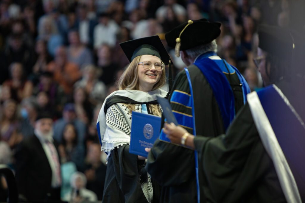 Katie Strubel receives a diploma for a master of fine arts in creative writing from President Sabah Randhawa.