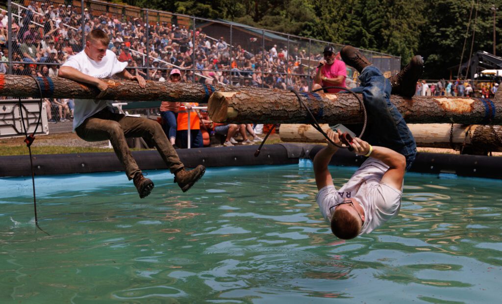 After slipping, Skyler Isaacson, right, hangs by his legs and sets his choker Saturday, June 8 while opponent Darren Schmidt also tries to get back up during the obstacle choker-setting competition at the Deming Logging Show in Deming.