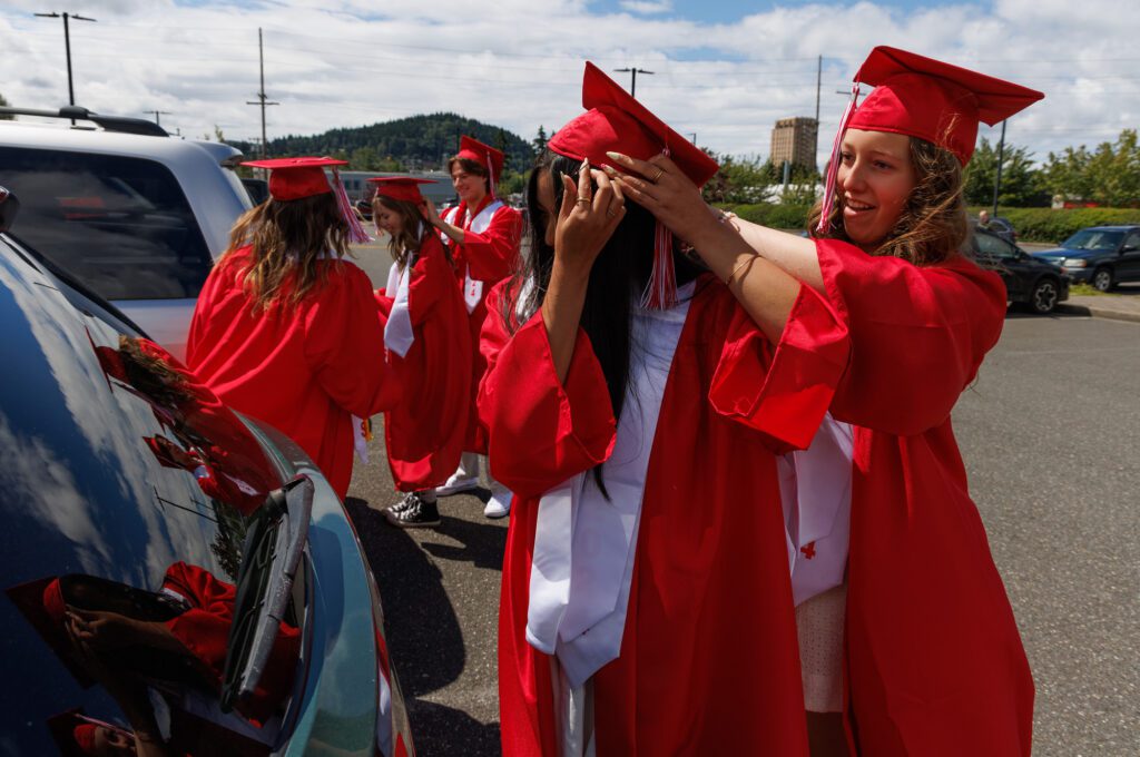 Bellingham graduate Catherine Chen gets help with her mortarboard by classmate Coco Haggen before their ceremony.