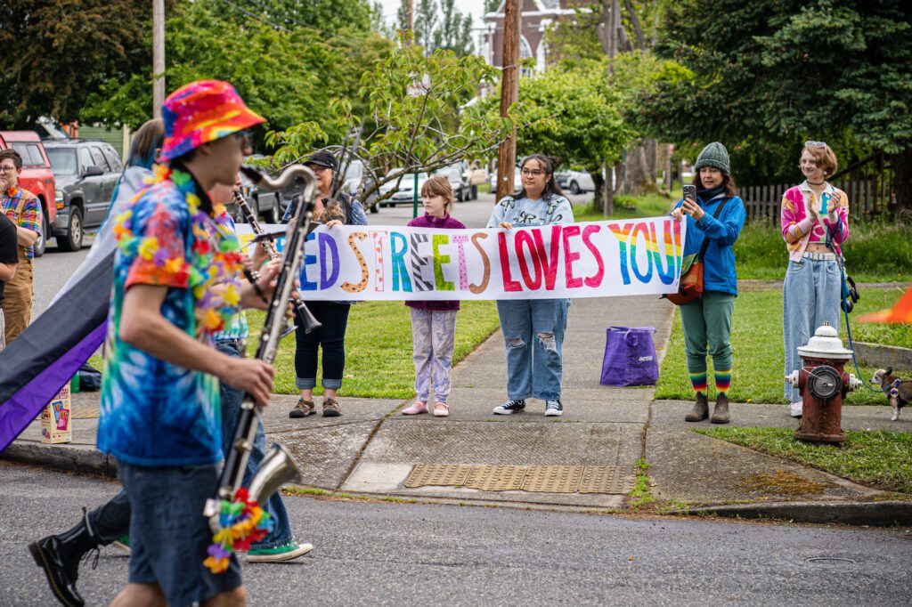 Lettered Streets residents hold a sign as the marching band passes by.