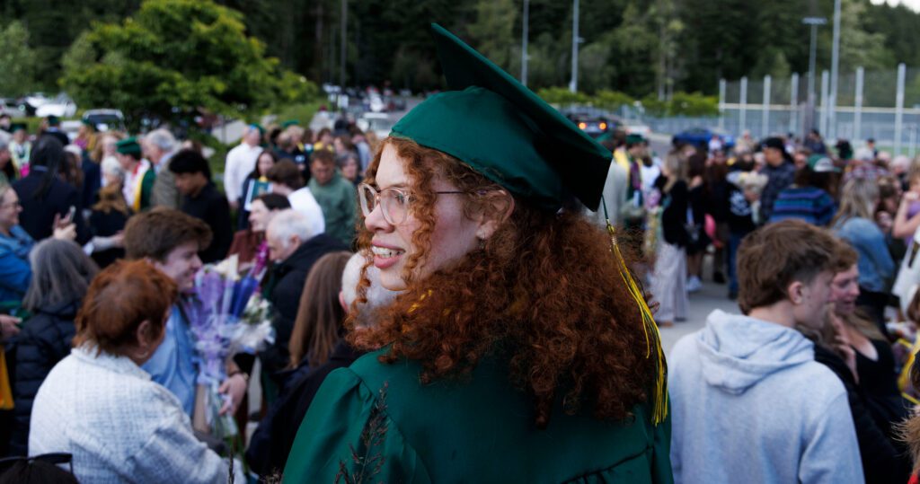 Standing on a high wall, Sehome graduate Sierra Marshall looks for family and friends.