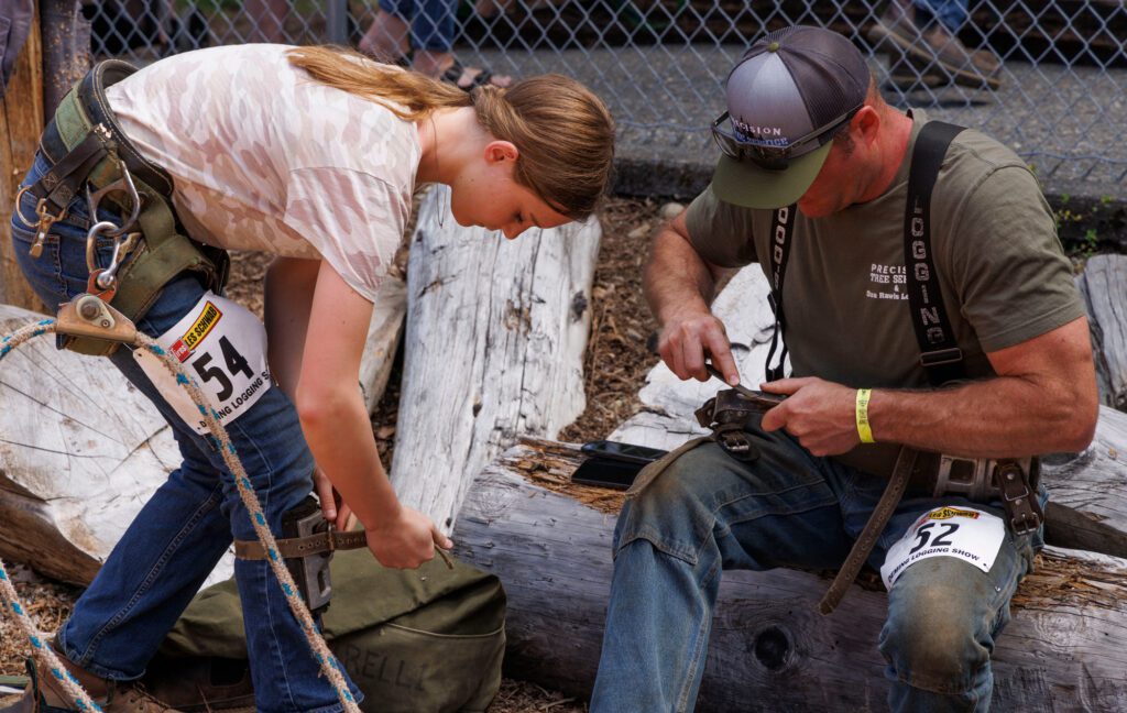 Dan Rawls sharpens the climbing spurs for Emory Rawls as she prepares her gear for pole climbing.