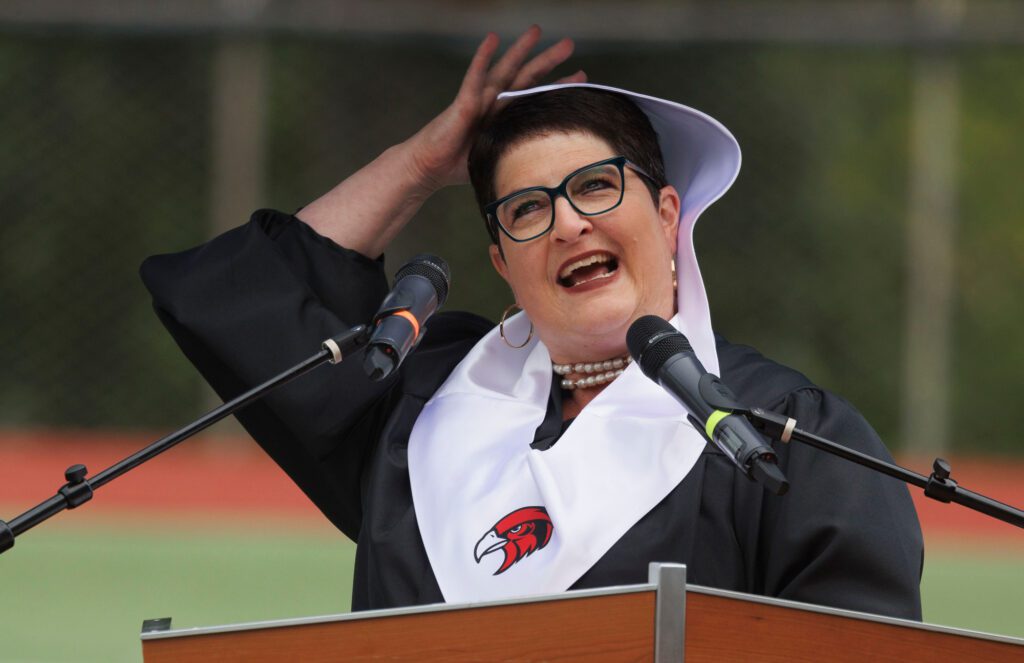 Bellingham faculty speaker Jen Reidel laughs as winds blows her collar up during her speech.