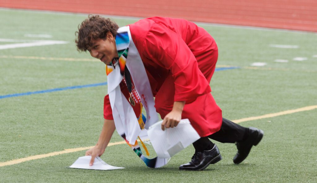 Bellingham student speaker Kaleb Payne picks up his speech notes as winds blow them off his podium.