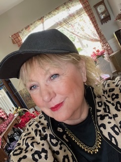 A woman wearing a black baseball cap and a leopard print shirt.