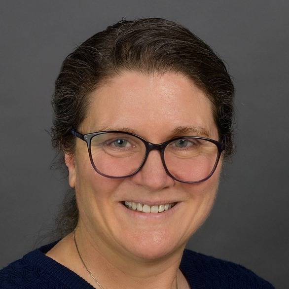 A white woman wearing glasses with her hair pulled back.