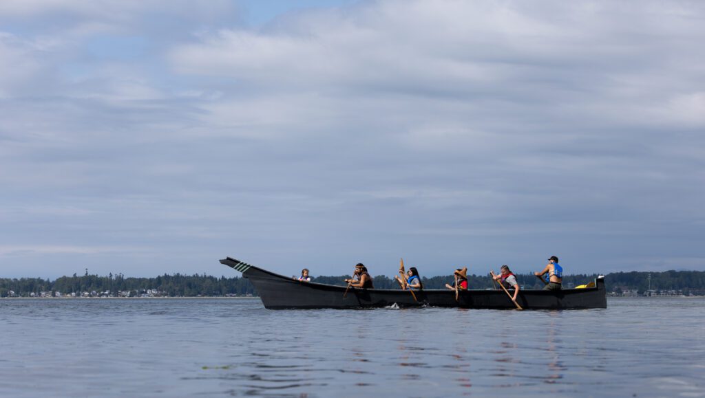 A canoe heads out on Birch Bay to meet the incoming canoe families.