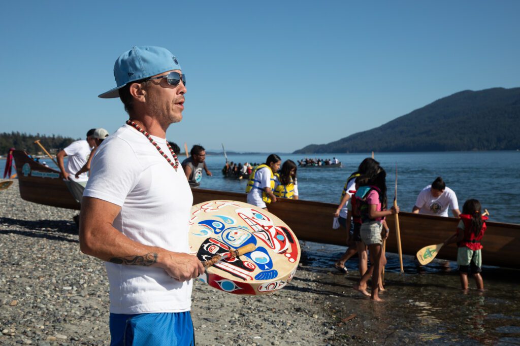 Sonny Curley of Quinault Indian Nation sings a prayer song while canoes enter the water at Gooseberry Point.