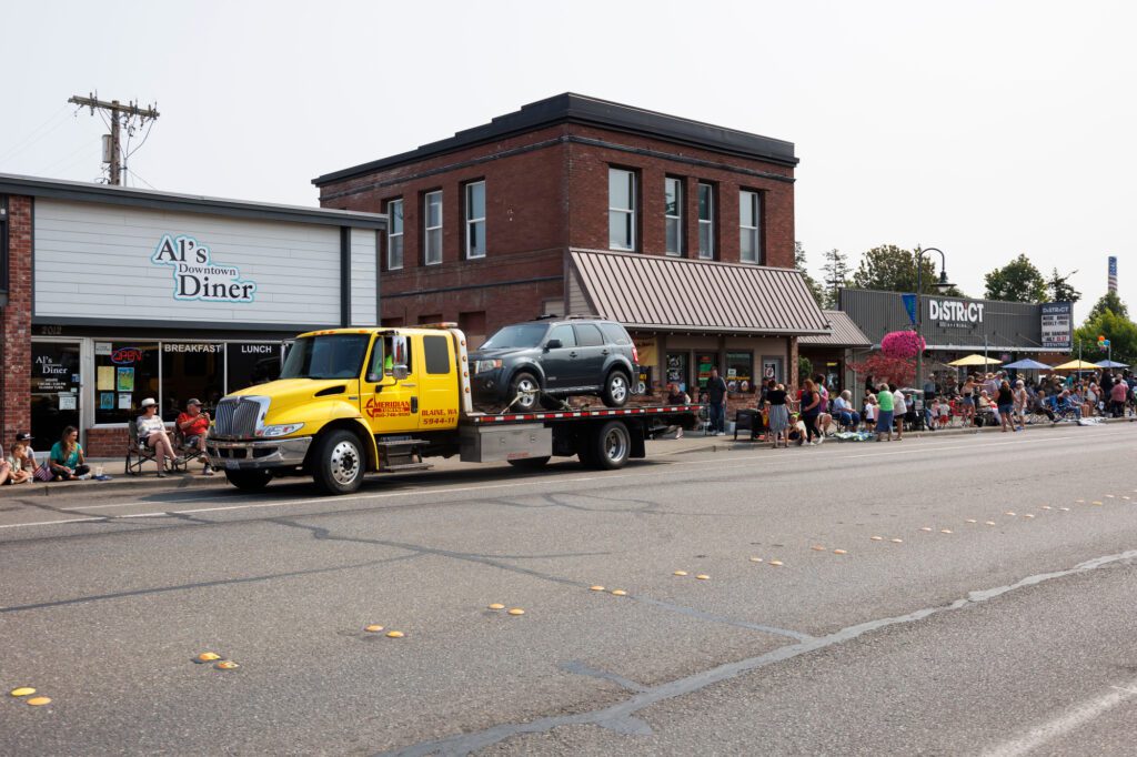 Spectators wait as a car is towed before the grand parade can start.