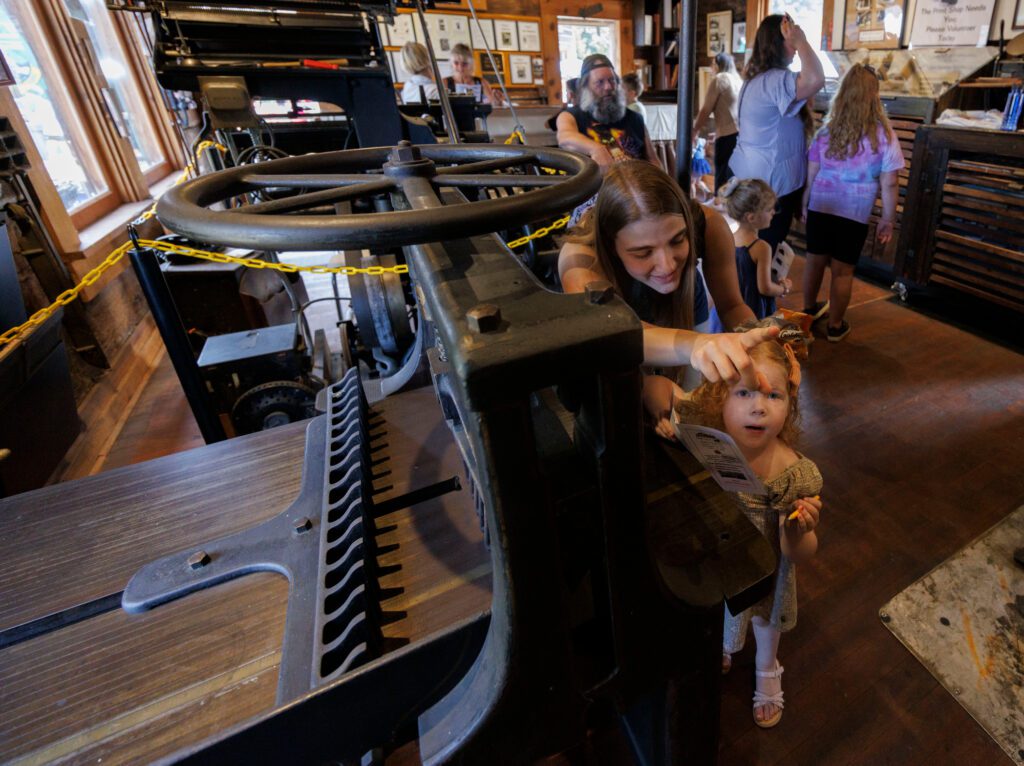 Lisa Barbo points to a gold star as she helps her niece Oakley, 3, fill out a passport book.