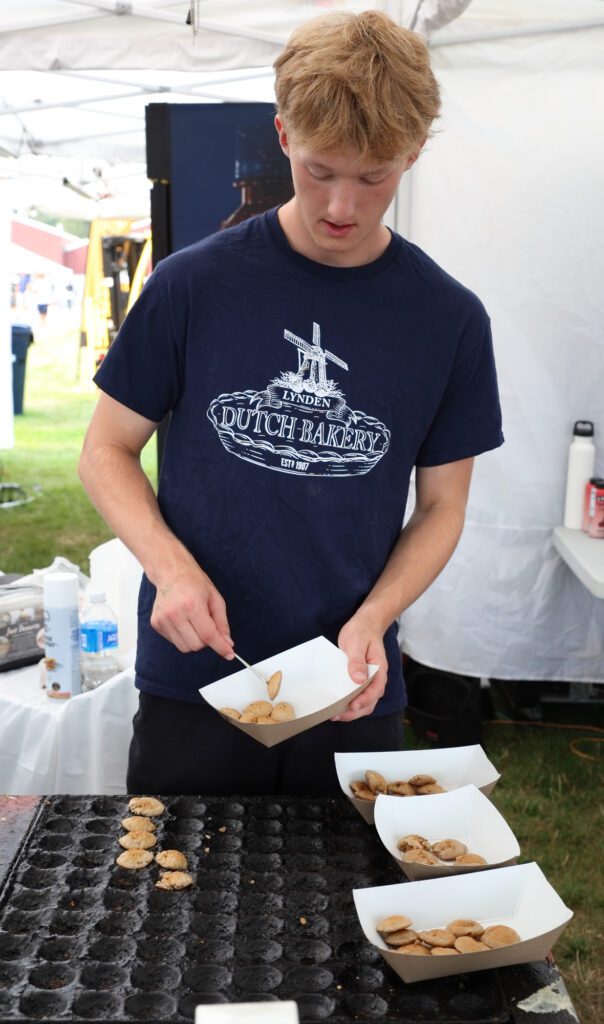 Kael Stapleton makes poffertjes, Dutch mini pancakes, at Lynden Dutch Bakery's annual booth. They make thousands of the tiny pancakes each day, filling the cast iron pans.