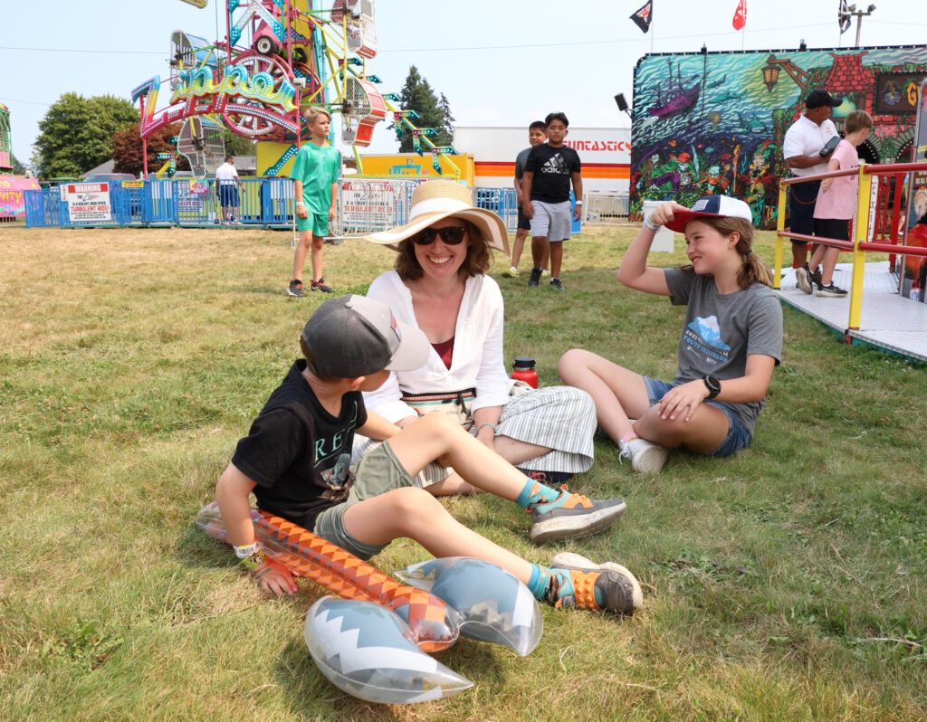 From left, Mip, Rachel and Margaux Barber sit in the grass in between enjoying rides.