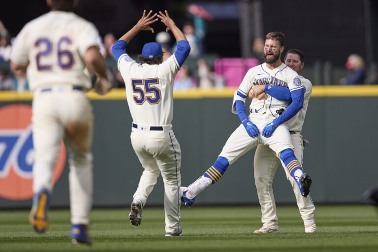 Seattle Mariners’ Jesse Winker, front right, is lifted by Ty France as another teammate rushes to celebrate with them.