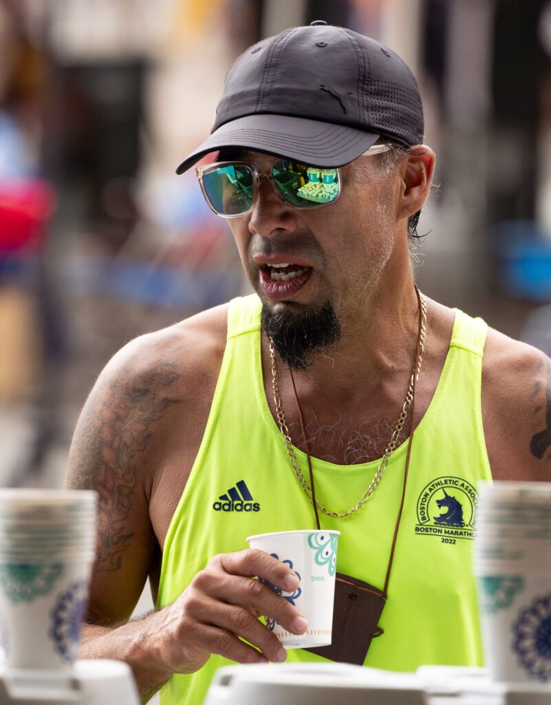 Rows of water cups are reflected in Sheridan Walker's glasses as he hydrates after completing the marathon.