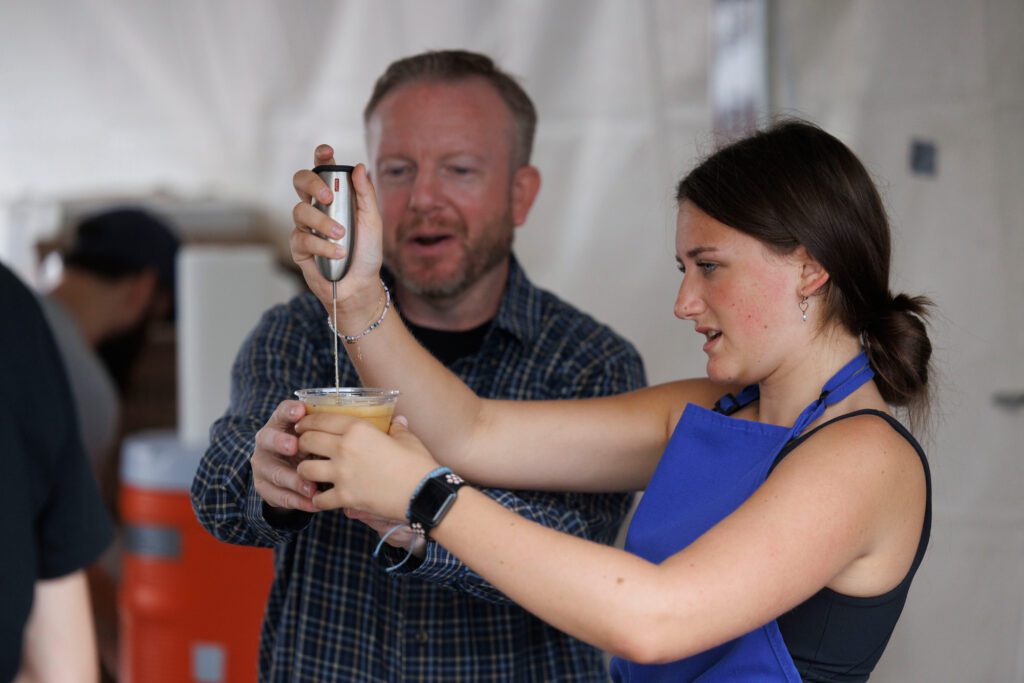 Nathan Michelson holds a cup still as Emeryst Evans mixes a Greek frappé coffee.