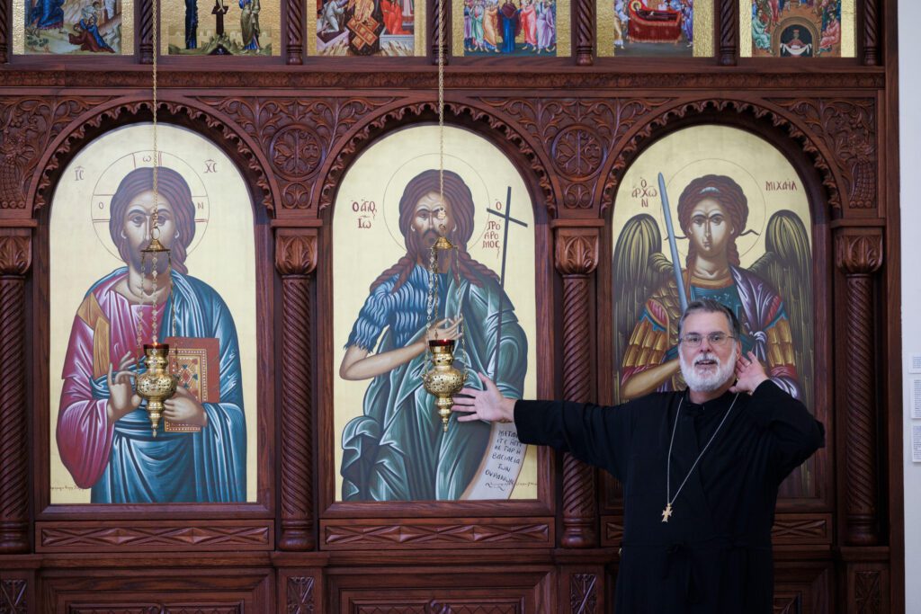 Father Michael Tervo bends an ear to hear an answer about who the paintings represents during a tour of St. Sophia’s church.