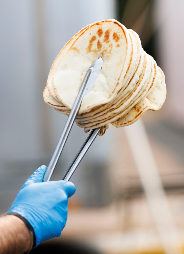 Pita bread is carried to servers to make gyros.