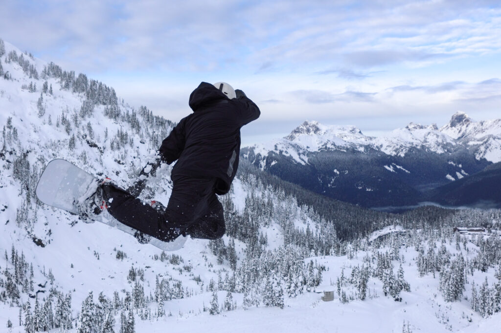 A snowboarder catches air on the Blueberry Cat Track as the day closes.