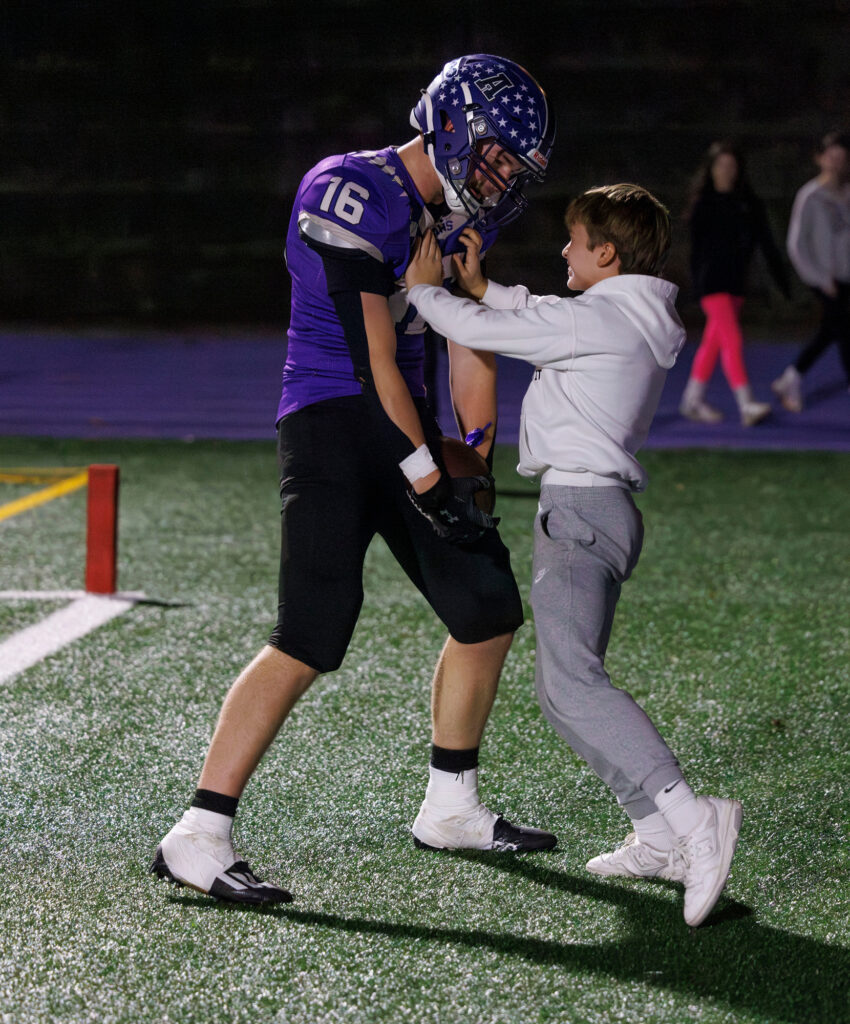 Anacortes' Micah Dickison celebrates his touchdown with young kids near the end zone.